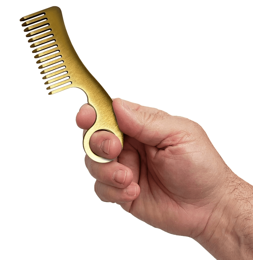 Hand holding a gold comb against a white background