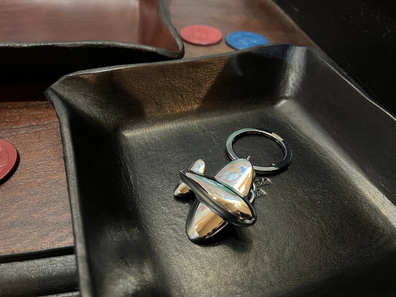 Troika Jetsetter cast airplane keychain shown in black leather desk tray