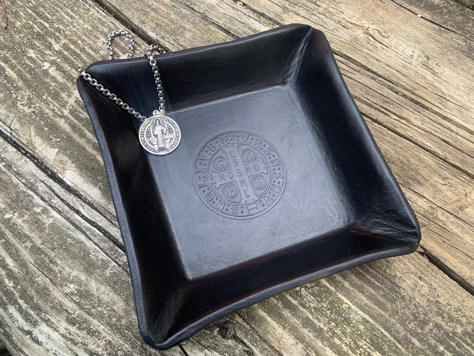 Black leather tray with image of St. Benedict medal.