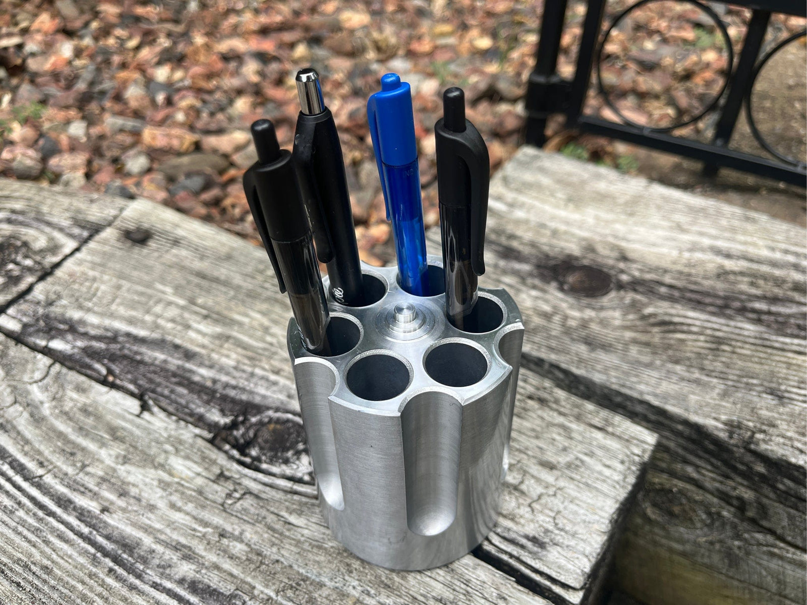Aluminum revolver barrel  pen holder with multiple pens on a wooden surface