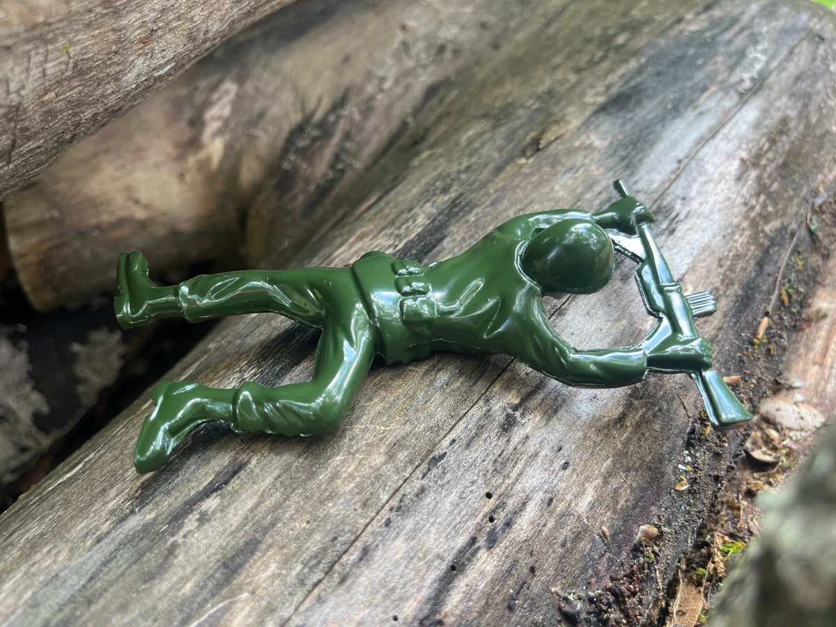Army man bottle opener shown on a log