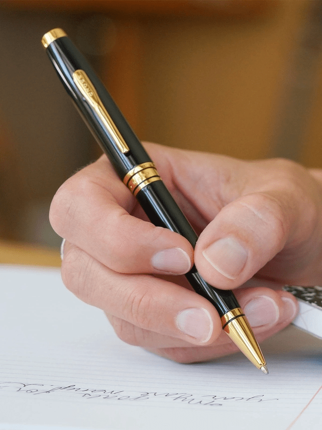 Hand holding black lacquer and goldtone A.T. Cross Pen