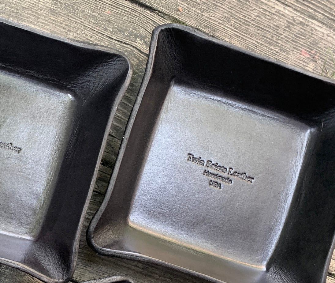 Two black leather trays with &#39;Twin Saints  Leather&#39; branding 