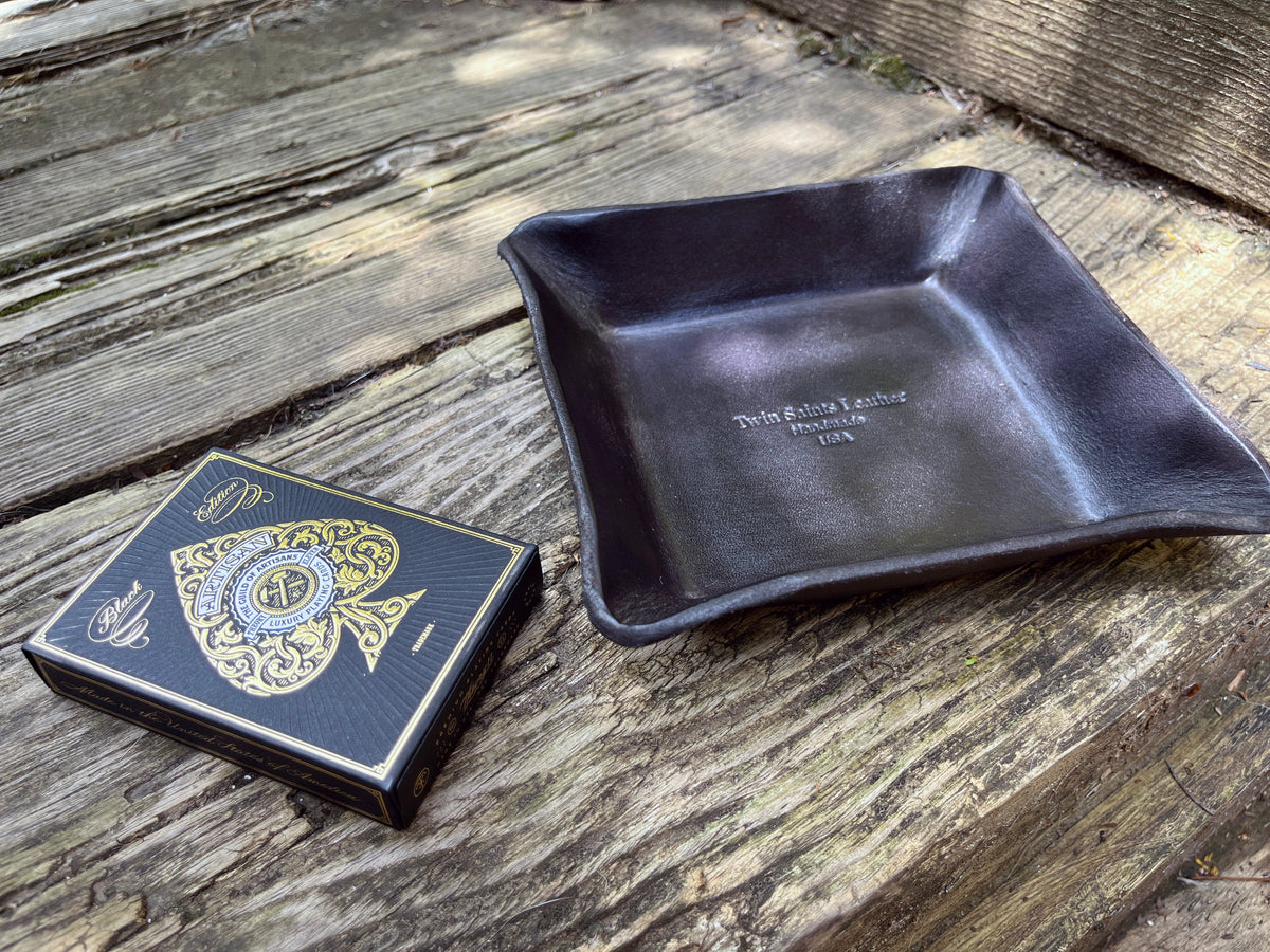 Twin Saints Black leather tray and deck of Theory 11 cards on a wooden surface
