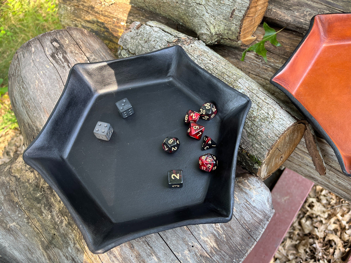 Black hexagonal tray with dice on a wooden surface