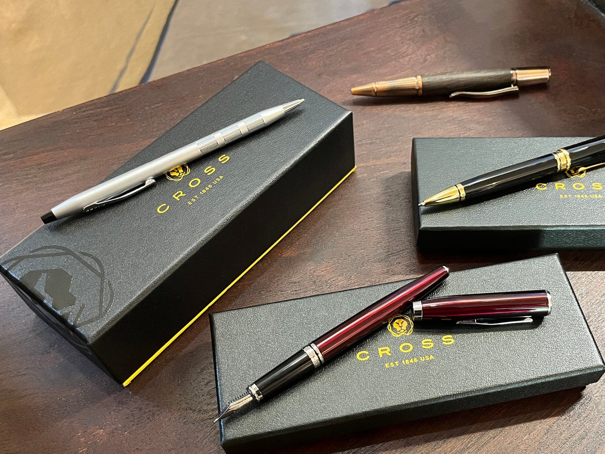 Classic ballpoint and fountain pens shown on a desk with boxes