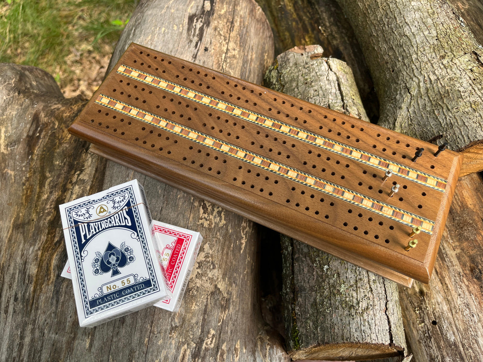 Top view of deluxe walnut wood cribbage set shown with two decks of cards and metal pins