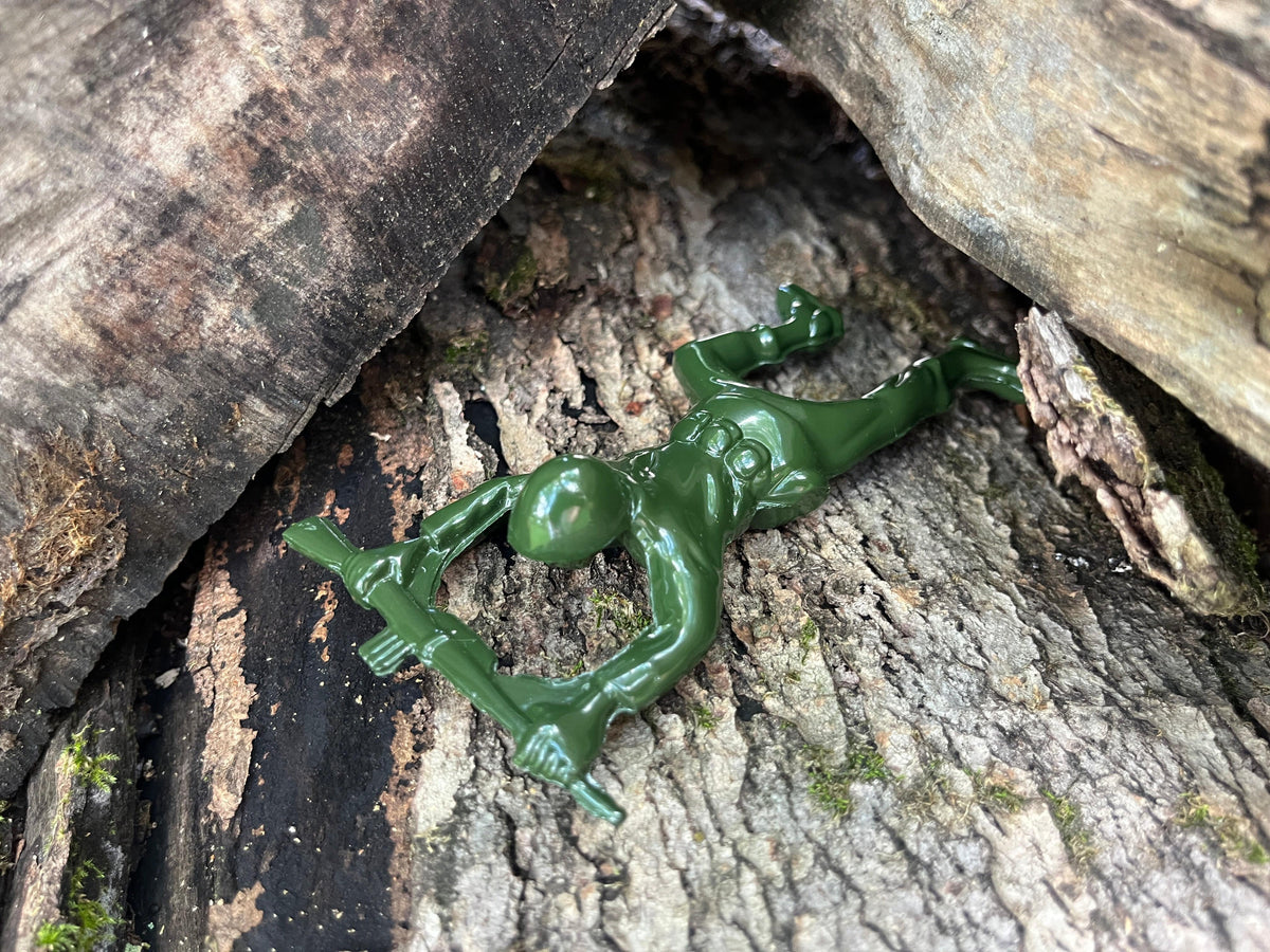 Green army man metal bottle opener shown on a wooden surface