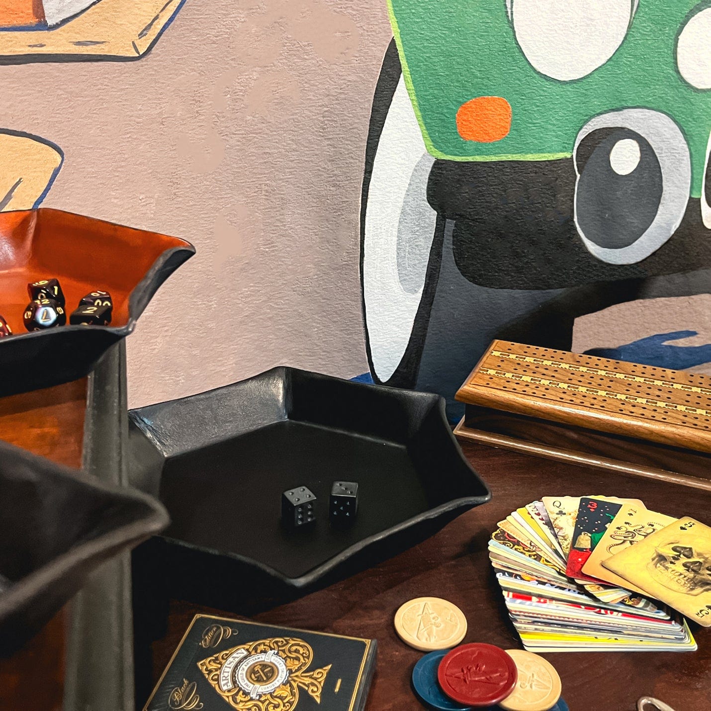 Game pieces including dice, cards, and poker chips on a table with a colorful abstract painting in the background.