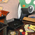 Game pieces including dice, cards, and poker chips on a table with a colorful abstract painting in the background.