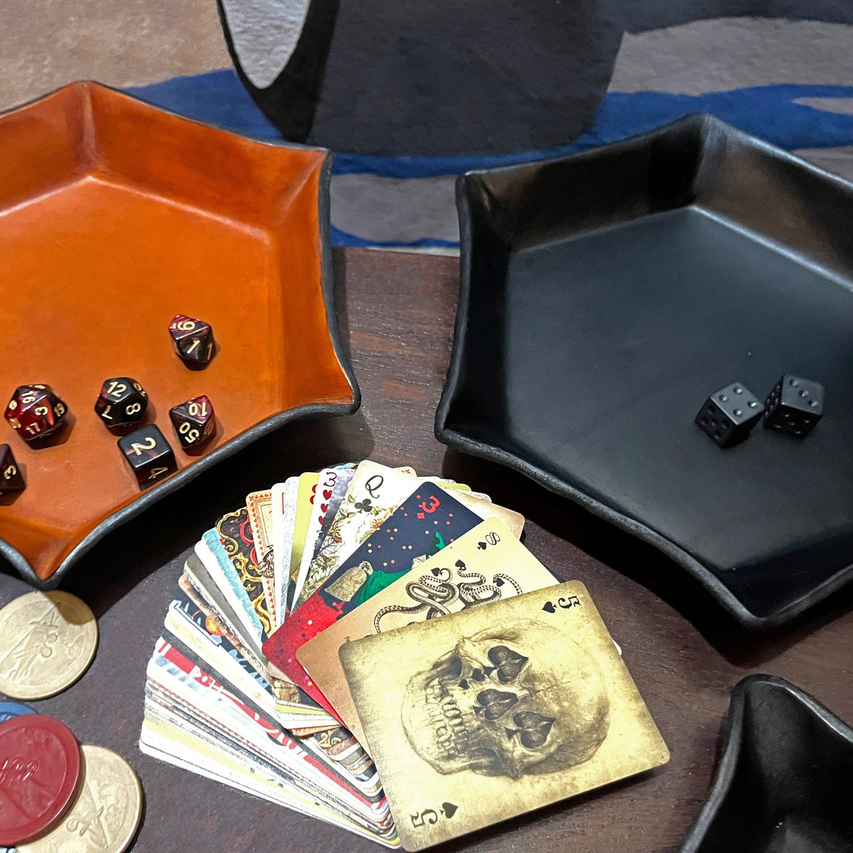 Two hexagonal dice trays, one brown and one black, with dice and playing cards on a table.