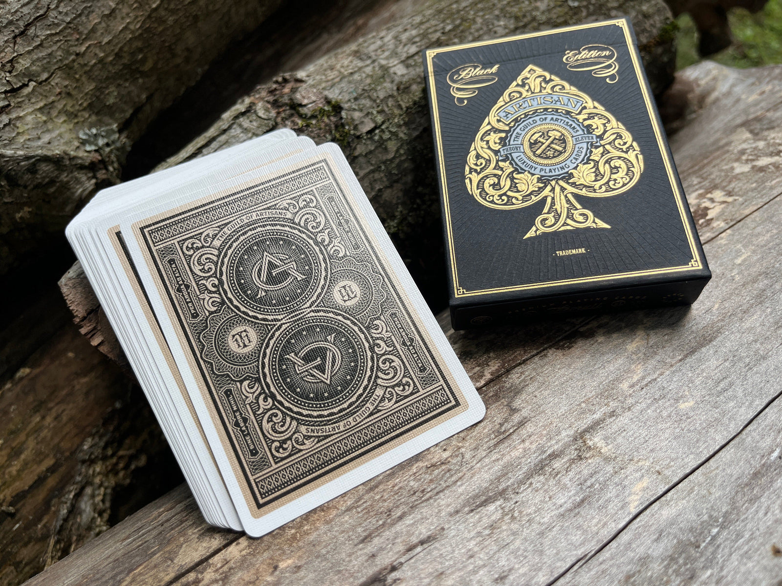 Black Artisan Playing cards with ornate designs on a wooden surface