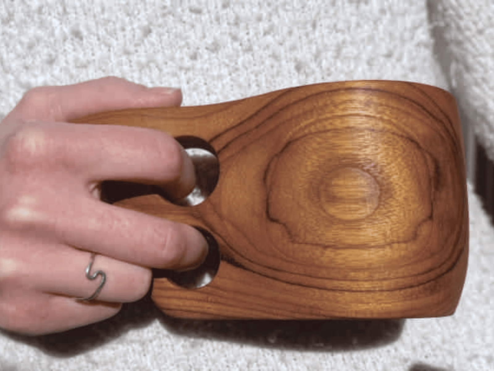 Eco-friendly teak Kuksa mug shown closup with person holding mug.