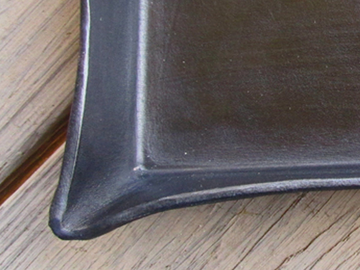 Corner detail of a black leather valet tray