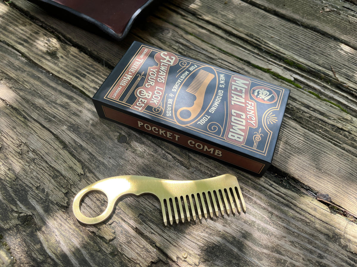 Brass pocket comb and branded box on a wooden surface