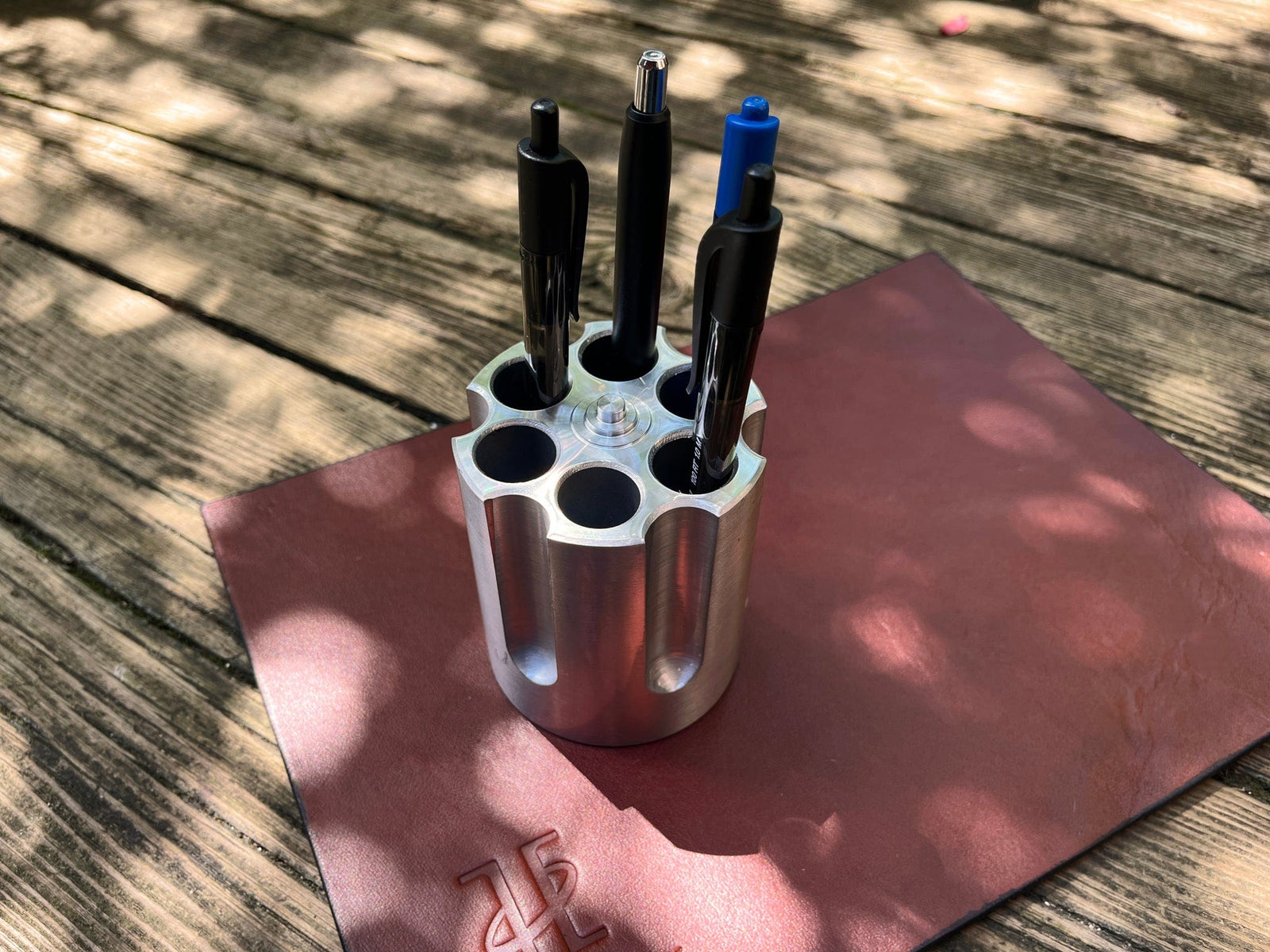 Metal pen holder with pens on a wooden surface