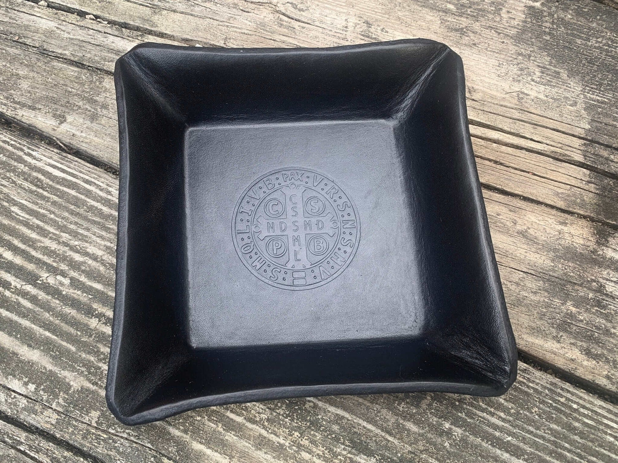 Detail of black leather tray with embossed St. Benedict Medal.